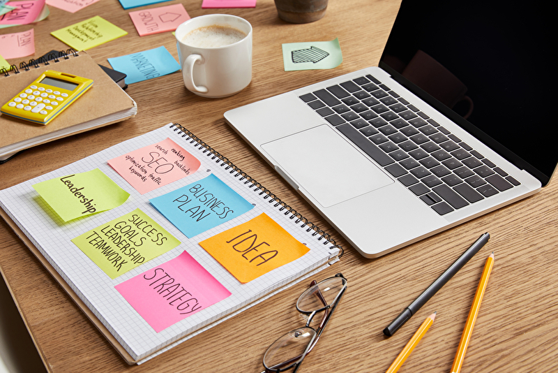 Papier Sticker mit Geschäftsstrategie, Gläser und Laptop auf Tischplatte